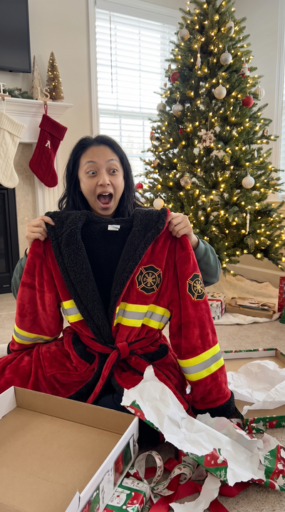 Woman opening gift box pulling out red Turnout Robe Christmas